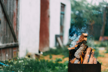 Chopped wood from fruit trees burning in the grill for barbecue in the yard or garden