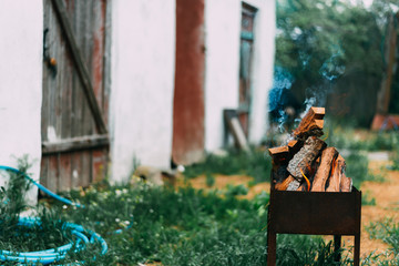 Chopped wood from fruit trees burning in the grill for barbecue in the yard or garden