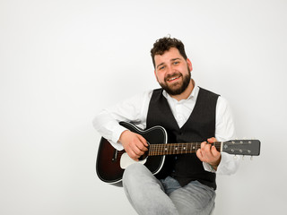 man with black hair and beard playing and singing with acoustic guitar on white background and is happy