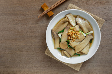 top view of stir fried king oyster mushroom with soy sauce in a ceramic dish on wooden table. asian homemade style food concept.