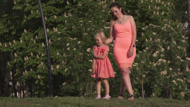 Happy mother playing with her little baby girl daughter and having fun - Young caucasian white mom wearing summer bright vivid color dress - Happinness family concept