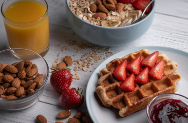 Traditional breakfast with belgian waffle and oatmeal with berry. Morning meal. Sweet dessert with fruit, nuts, juice and jam