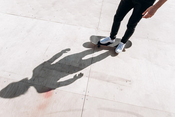 Fototapeta na wymiar The shadow of the man standing on the skateboard on the floor of slide in a skate park at the sunny day outside