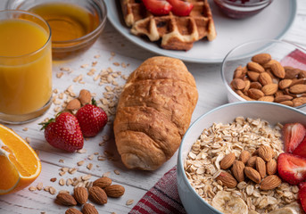 Breakfast - traditional delicious belgian waffle, sweet croissant and fruit oatmeal porridge with berry, fruit and nuts on white background top view. Morning food set