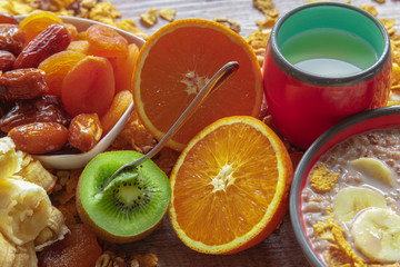 Homemade granola with milk, banana, fresh kiwi, milk and dried plums with dates for breakfast