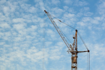 Industrial construction building crane against blue cloudy sky