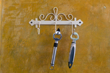 Two Bottle opener hanging on orange cement wall.