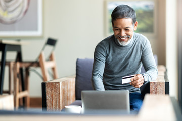 Attractive bearded hipster asian father or Hispanic old man using Laptop and credit card payment shopping online with customer network connection via omni channel system. Older man with technology. - Powered by Adobe