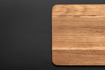 top view of empty wooden cutting board on black background