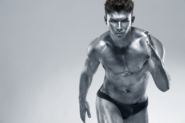 Runner or sprinter concept. Brutal strong muscular bodybuilder athletic man run on light...