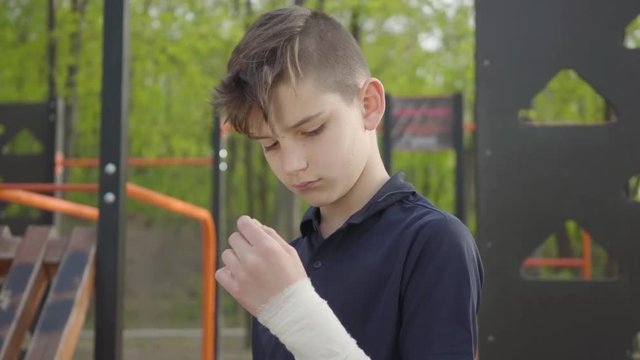 Young boy with bandaged hand in the playground. Kid want to play but he is injured