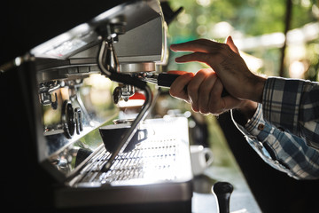 Image closeup of professional barista man making coffee while working in cafe or coffeehouse outdoor