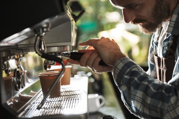 Image closeup of handsome barista man making coffee while working in cafe or coffeehouse outdoor