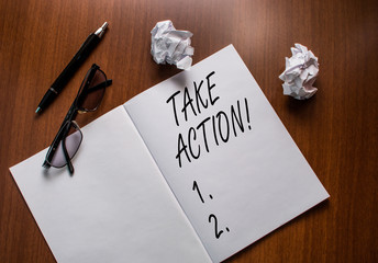 Conceptual hand writing showing Take Action. Concept meaning do something official or concerted to achieve aim with problem Notebook small wrinkled paper balls reading glasses wooden table