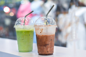 Close up ice dark cocoa with fresh milk in plastic cup to take home at coffee shop.