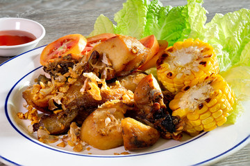 Chicken fried and vegetable on white dish and chili sauce on wooden table thai food