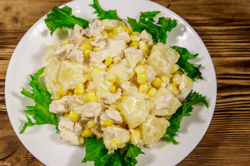 Festive salad with chicken breast, sweet corn, canned pineapple and mayonnaise on wooden table