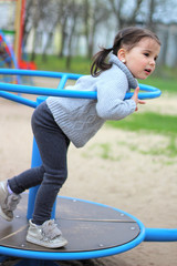 child rides on the carousel in the playground