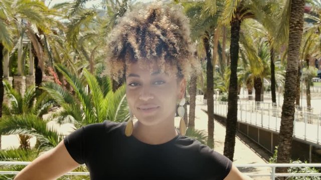 Trendy ethnic woman in sunlight on street 