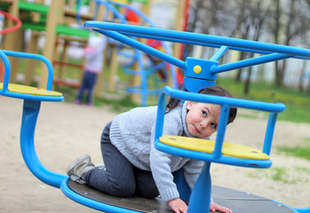 child rides on the carousel in the playground