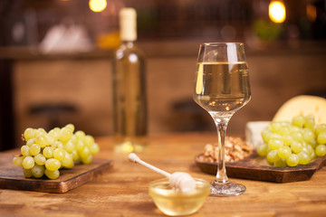 Close up of a glass of wine next to a bowl of tasty golden honey on a wooden table in a vintage pub