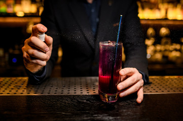 Close shot of bartender spraying to the alcohol cocktail