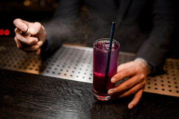 Close shot of bartender spraying to alcohol cocktail