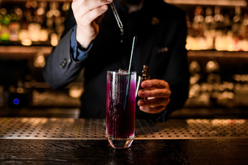 Male Bartender makes alcohol cocktail with dropper