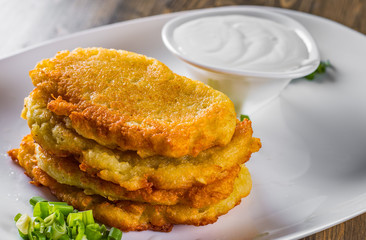 potato pancakes with sour cream in a plate on wooden table