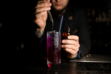 Male Bartender pours alcohol cocktail with dropper