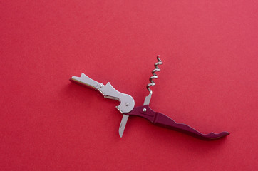 Opened sommelier's knife with corkscrew and bottle opener, waiter's knife professional, on red...