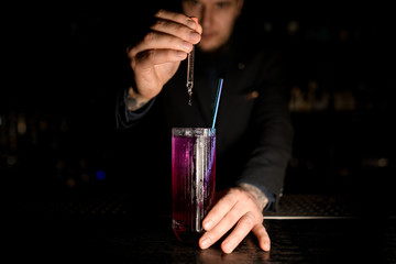 Male Bartender making a cocktail with dropper
