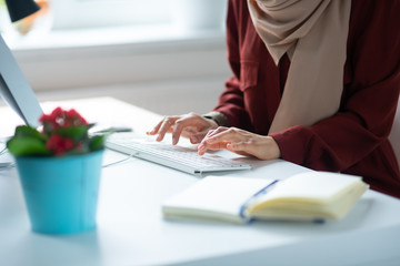 Close up woman typing on keyboard while sitting at the table