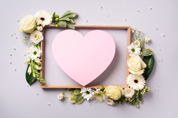 Creative layout with pink flowers, paper heart over grey background. Top view, flat lay. Spring,...