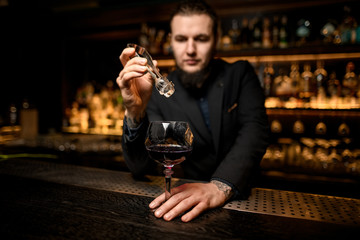 Bartender adds ice cube in alcohol cocktail