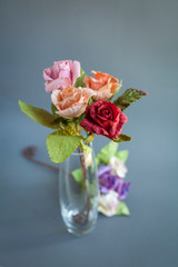 Beautiful rose paper flower in clear glass vase over blurred grey background, valentine gift, handmade paper flower