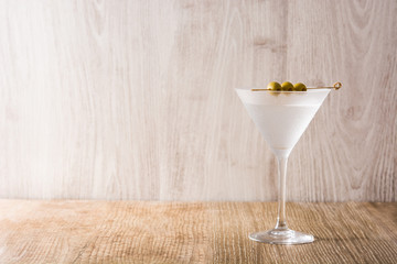 Classic Dry Martini with olives on wooden table. Copyspace