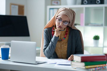 Teacher wearing glasses holding pen correcting tests