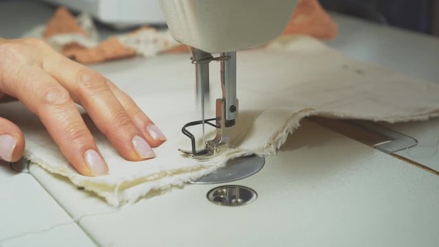 Woman tailor working on sewing machine. Tailoring process.
