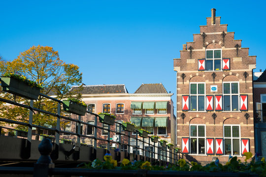 typical old Dutch house with facade and shelters, bridge with flowers, harbor in fortified city Gorinchem, The Netherlands