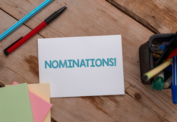 Conceptual hand writing showing Nominations. Concept meaning action of nominating or state being nominated for prize Note papers and stationary placed sideways softhued backdrop