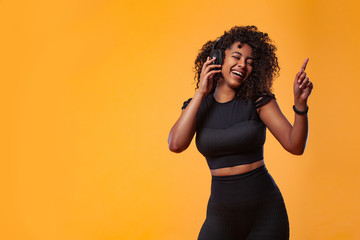Lifestyle Concept. Portrait of beautiful African American woman with curly hair joyful listening to...