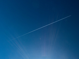 scia di un aereo nel cielo con raggi solari - obrazy, fototapety, plakaty