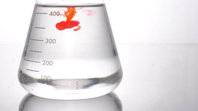 Clear liquid mixed with a red colored chemical reagent, red solution drop in flask experiment research laboratory
