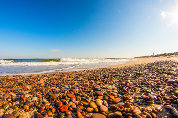 lonesome beach of the Baltic Sea with pebbles, surf and blue sky