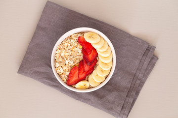 Oatmeal muesli in a bowl with strawberries, banana and flax seeds. Healthy breakfast.