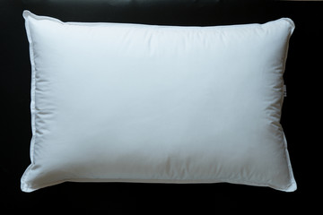 Close-up of white pillow isolated on a black background.