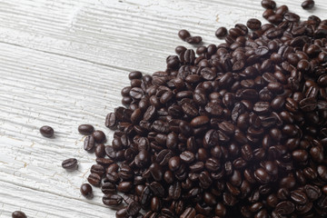 close up of pile roast coffee beans on wooden board