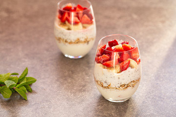 Homemade yogurt parfait with granola, strawberries, bananas and Chia seeds in glasses. Diet dessert with yogurt, Chia, muesli and fresh berries. Healthy breakfast 