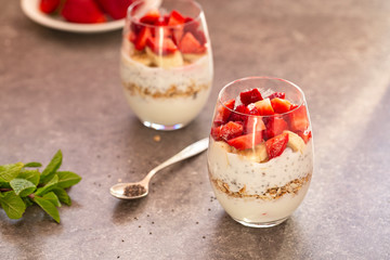 Homemade yogurt parfait with granola, strawberries, bananas and Chia seeds in glasses. Diet dessert with yogurt, Chia, muesli and fresh berries. Healthy breakfast 